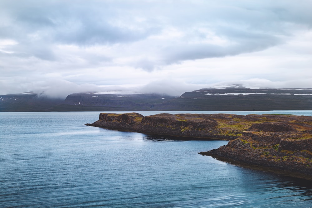 green and brown island on blue sea under white clouds during daytime