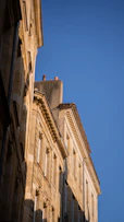 low angle photography of beige concrete building under blue sky during daytime