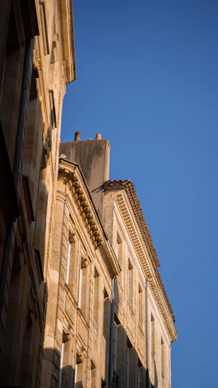 low angle photography of beige concrete building under blue sky during daytime