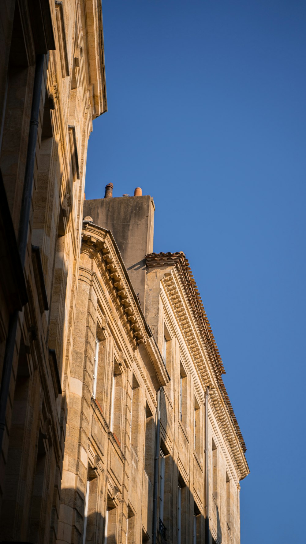 low angle photography of beige concrete building under blue sky during daytime