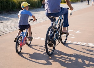 man in blue t-shirt riding on black bicycle during daytime