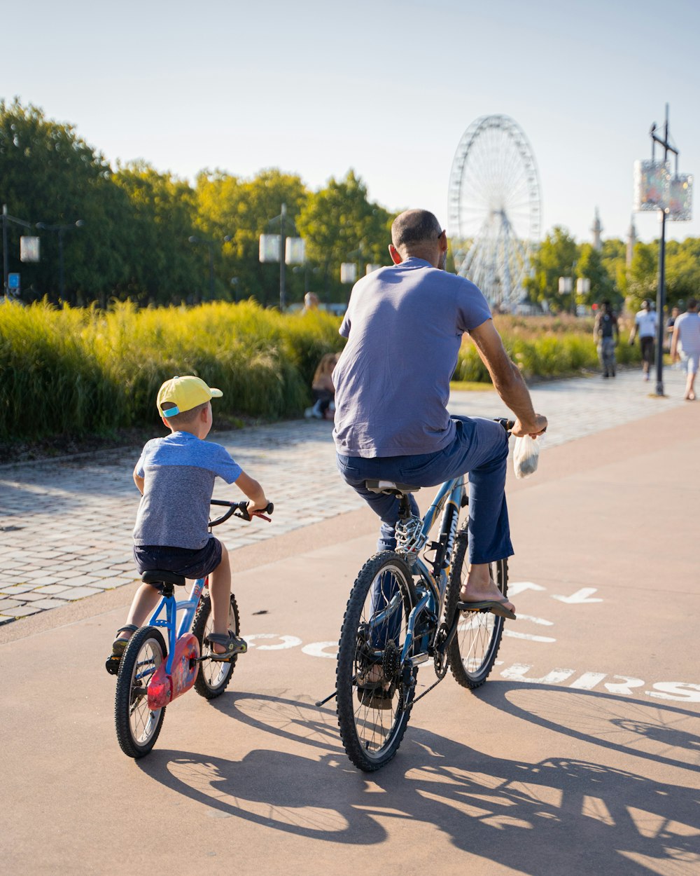 man in blue t-shirt riding on black bicycle during daytime