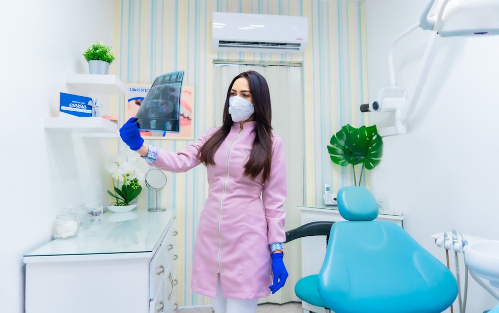 Femme en chemise rose à manches longues tenant un pichet en plastique bleu et blanc