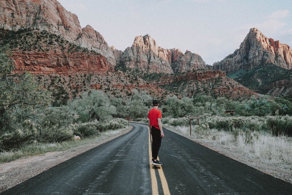 donna in camicia rossa a maniche lunghe e pantaloni neri che camminano sulla strada durante il giorno