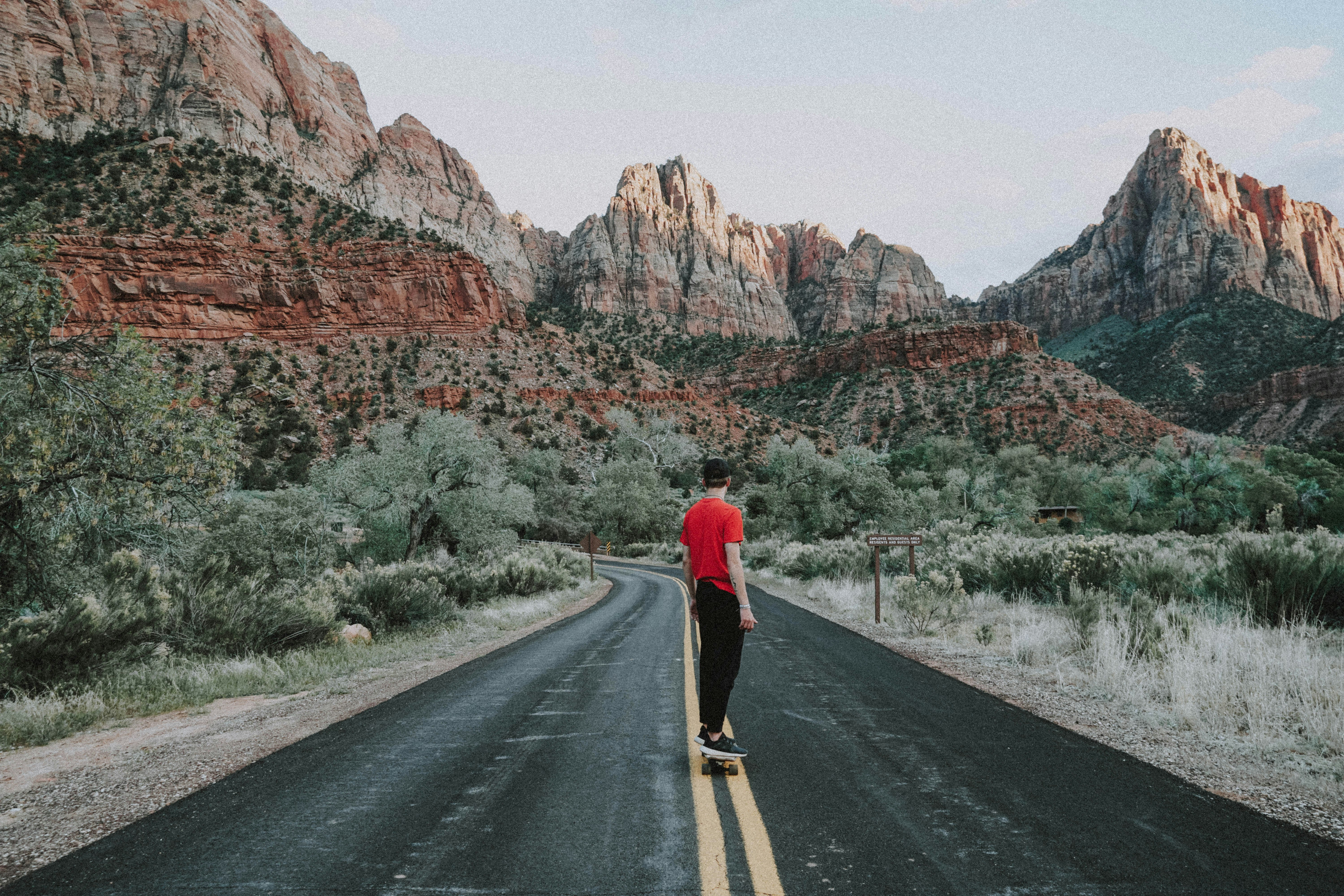 woman in red long sleeve shirt and black pants walking on road during daytime