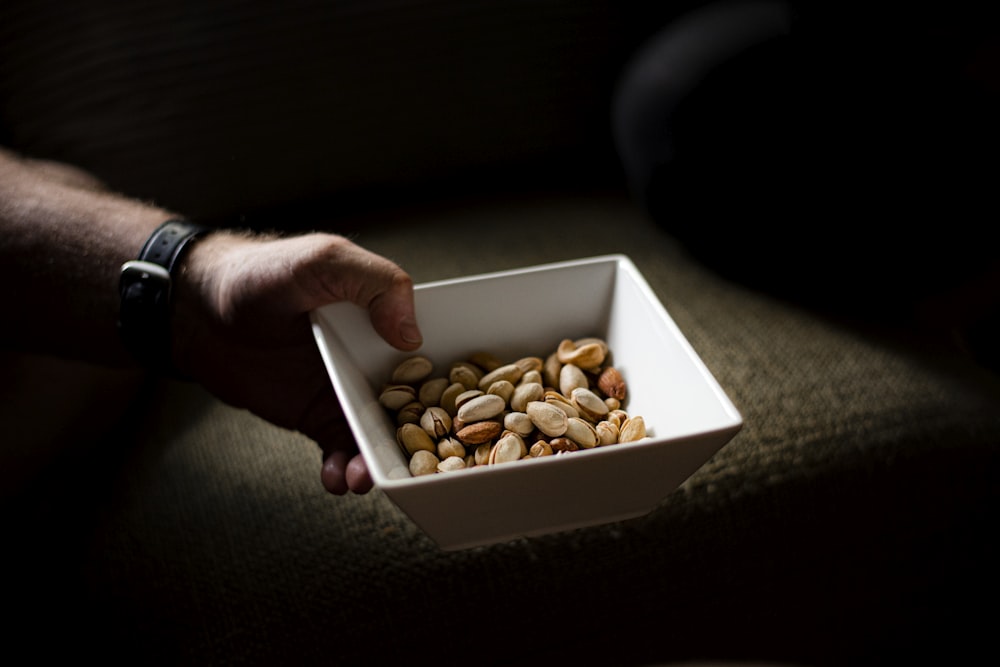 person holding brown and white nuts in white box