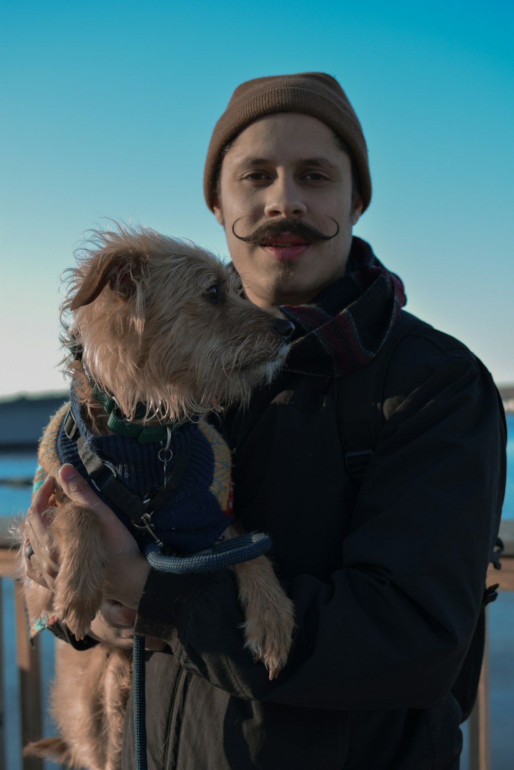 man in black jacket carrying brown long coated dog