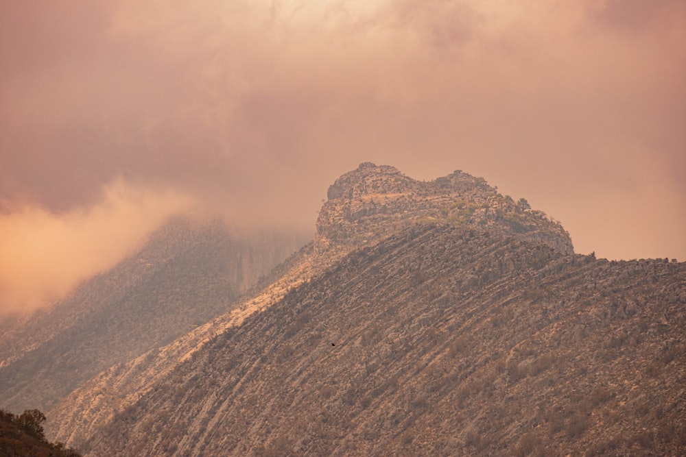 brown rocky mountain under white clouds during daytime