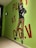 A mural features a stylized figure dressed in a black top and orange striped pants, posing with one hand on the hip and the other arm extended upward. The words 'PLAY AT C.G.V' are written in bold red and black letters on a bright green wall.
