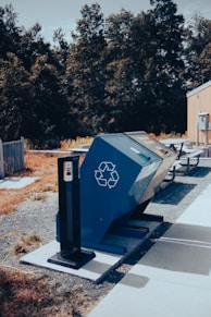 blue trash bin beside road during daytime