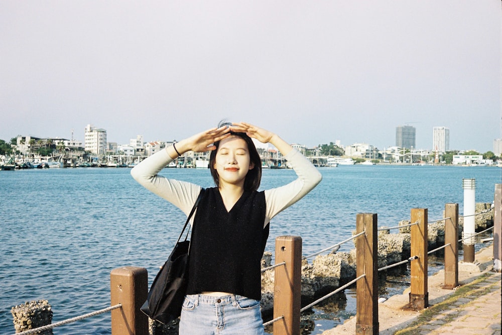 woman in black long sleeve shirt and blue denim jeans standing on brown wooden dock during