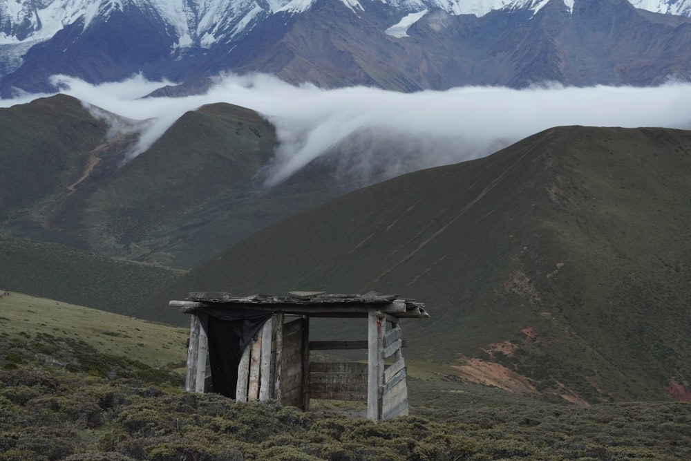 brown wooden house on green grass field near snow covered mountain during daytime