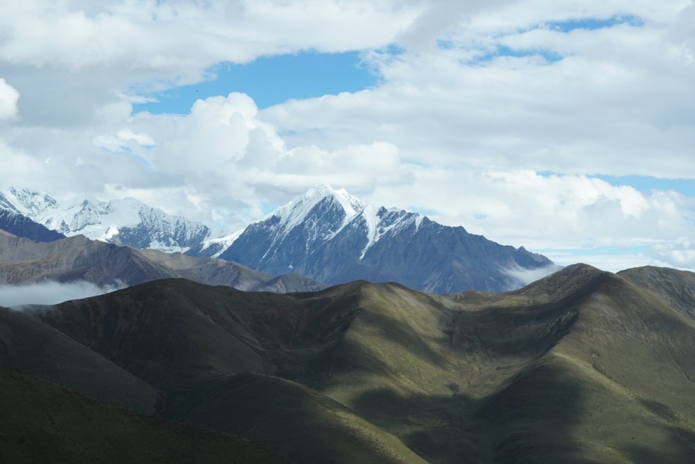 green and brown mountains under white clouds and blue sky during daytime