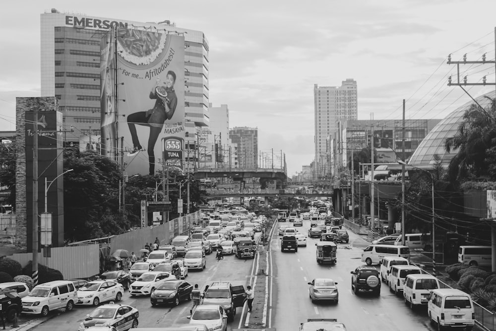 grayscale photo of cars on road near city buildings