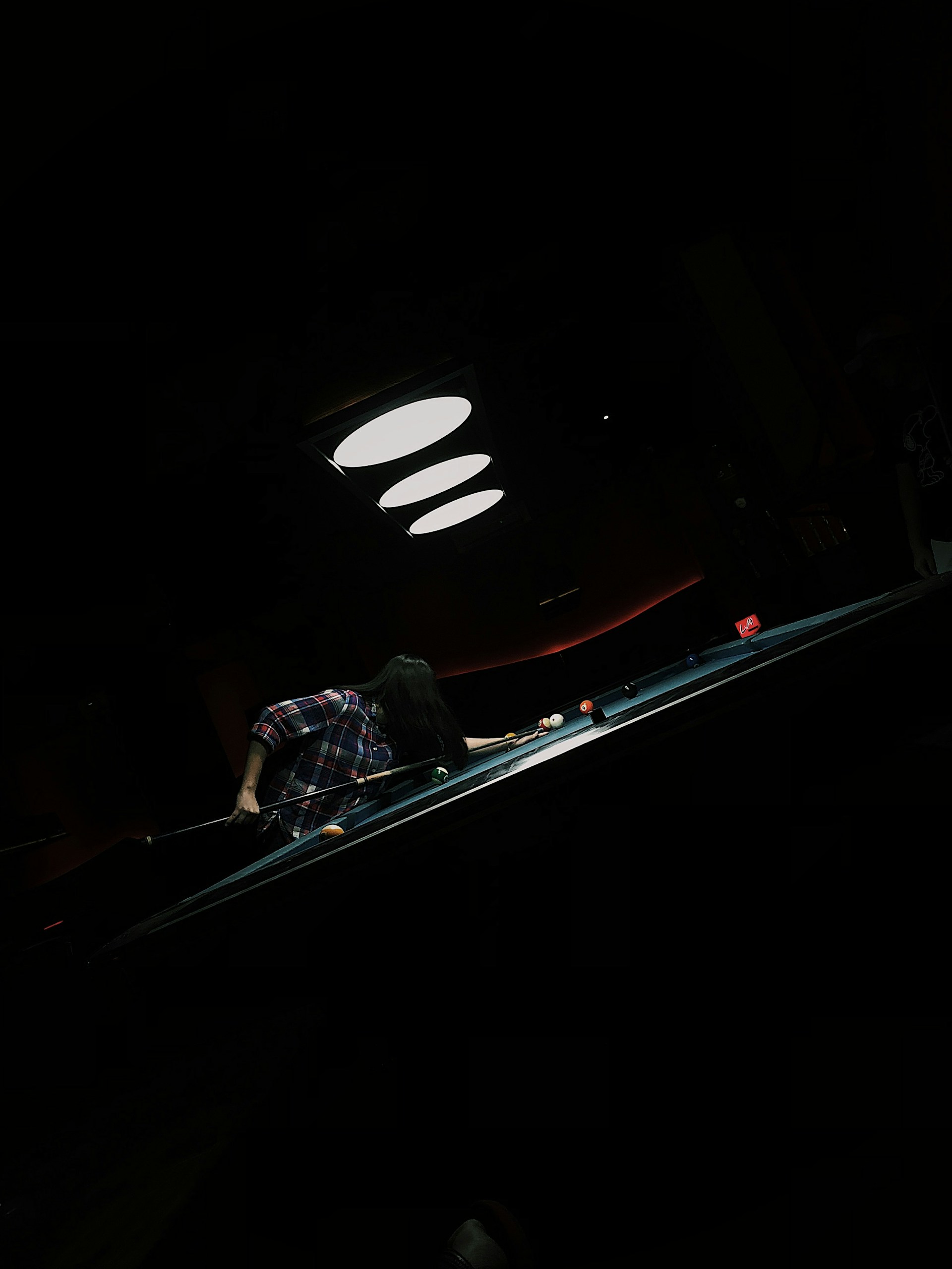 A lively shot of players intensely focused on their snooker game under the club's vibrant lighting.
