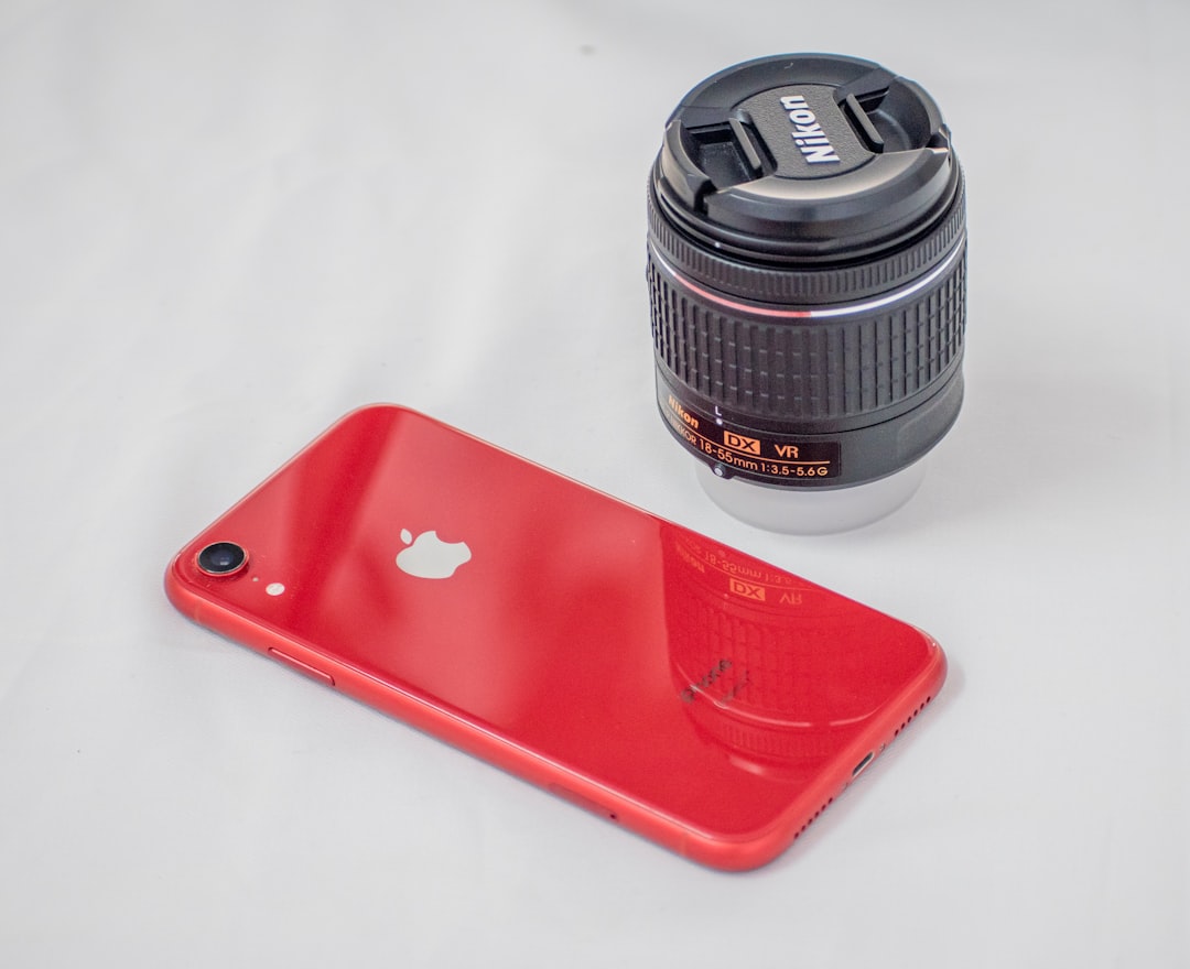 red iphone case beside black camera lens