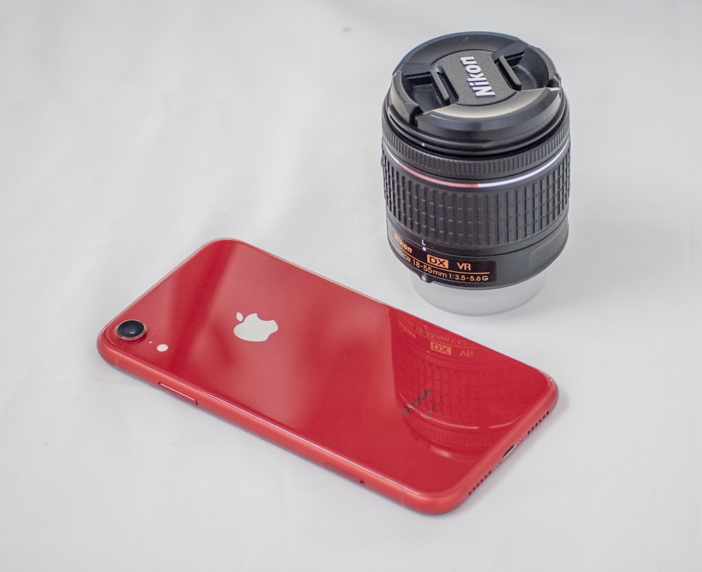 red iphone case beside black camera lens