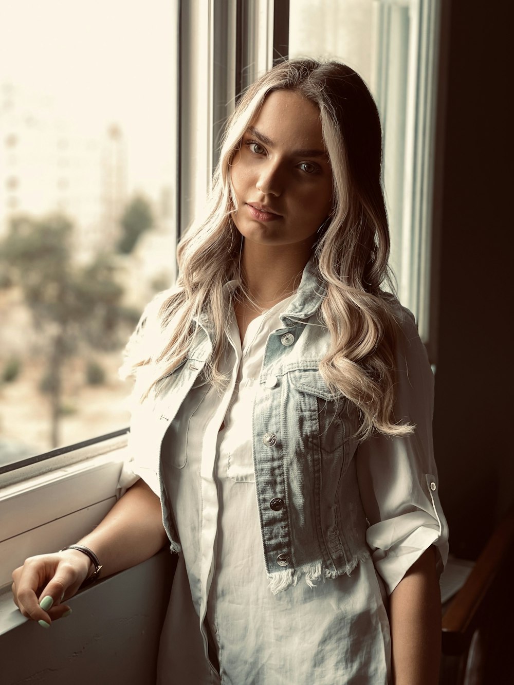 woman in white button up shirt sitting beside window during daytime