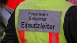 A high-visibility jacket with 'Feuerwehr Salzgitter Einsatzleiter' written on the back, indicating it belongs to a fire department operations leader. The jacket features reflective strips and appears worn by someone involved in emergency services.