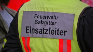 A high-visibility jacket with 'Feuerwehr Salzgitter Einsatzleiter' written on the back, indicating it belongs to a fire department operations leader. The jacket features reflective strips and appears worn by someone involved in emergency services.