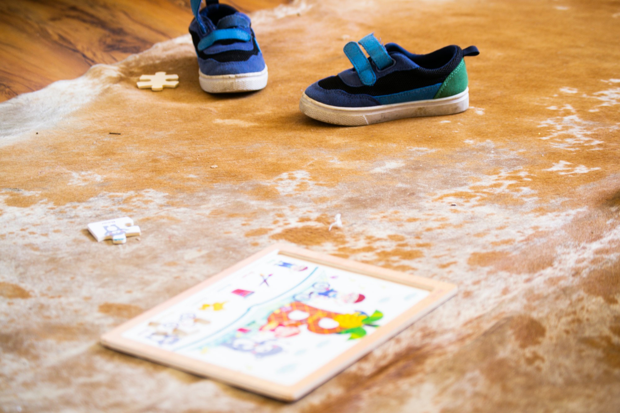 A jigsaw puzzle and a pair of baby shoes on top of a brown mat.