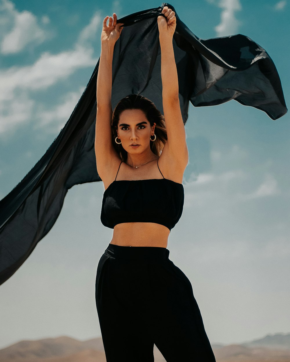 woman in black brassiere and black pants holding black and white textile