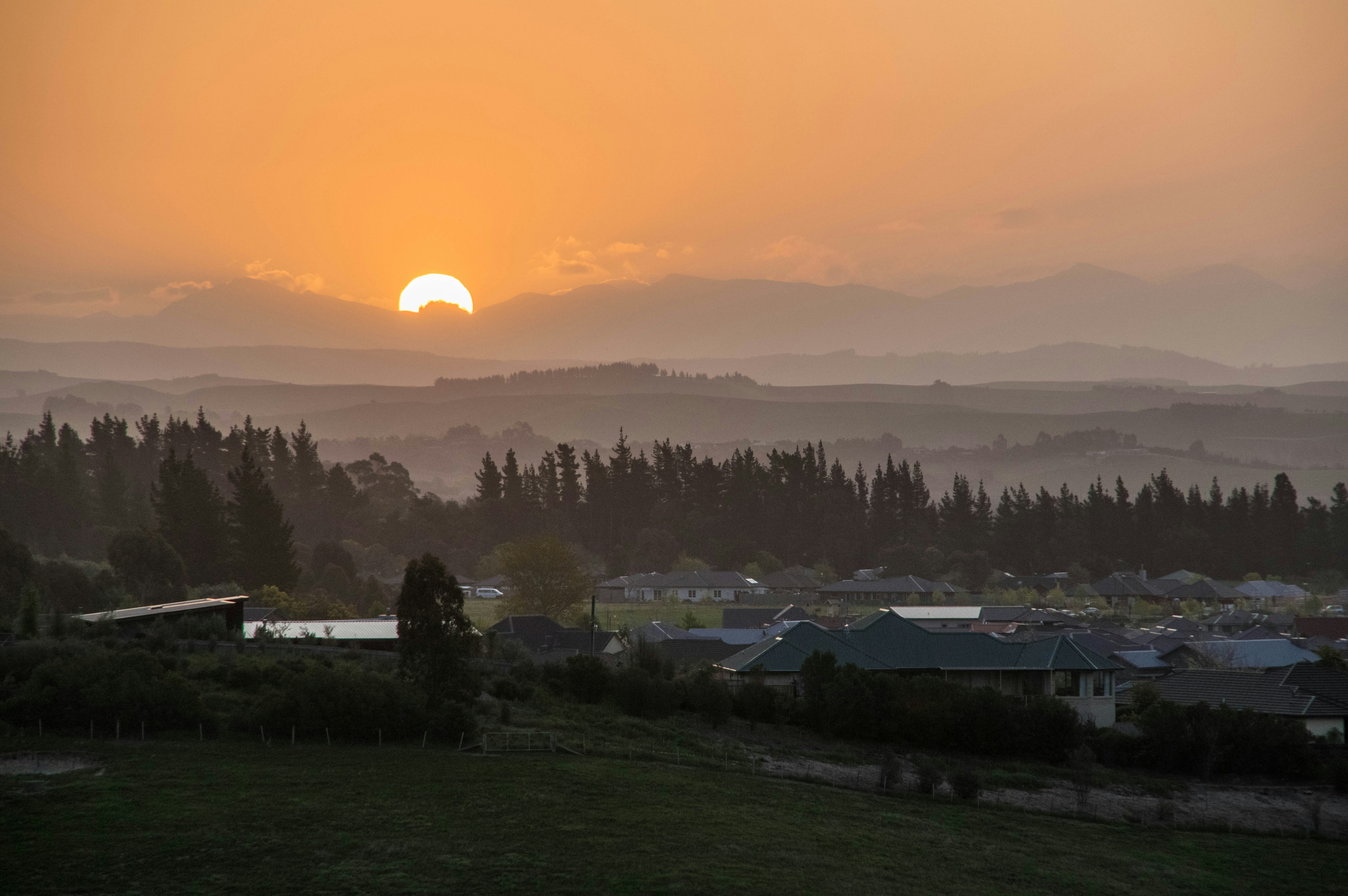 Häuser auf grünem Rasenfeld bei Sonnenuntergang