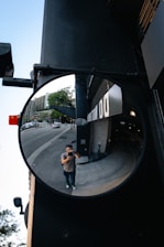 man in brown jacket and black pants carrying brown backpack walking on sidewalk during daytime
