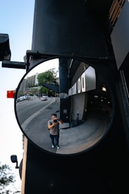 man in brown jacket and black pants carrying brown backpack walking on sidewalk during daytime