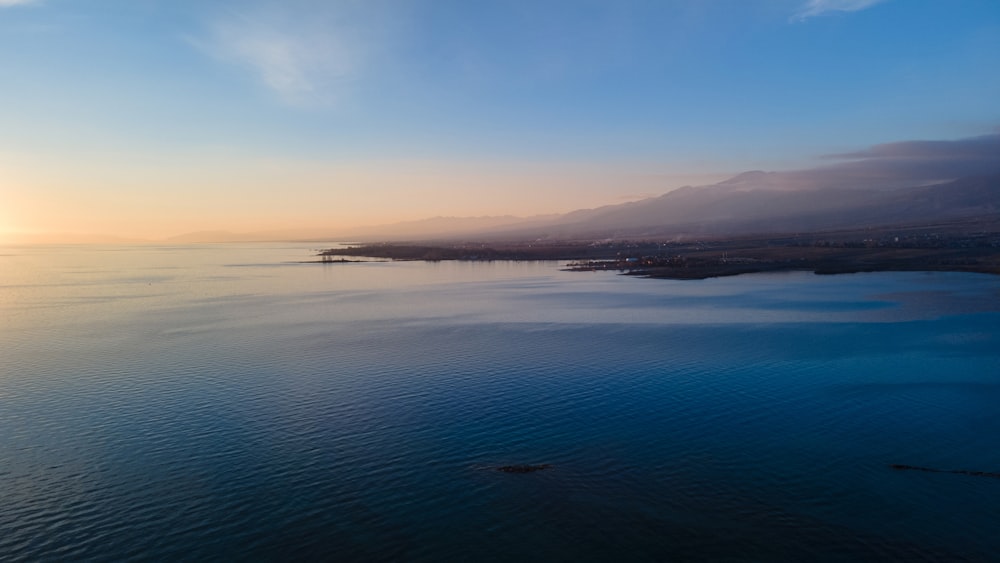 body of water near mountain during daytime