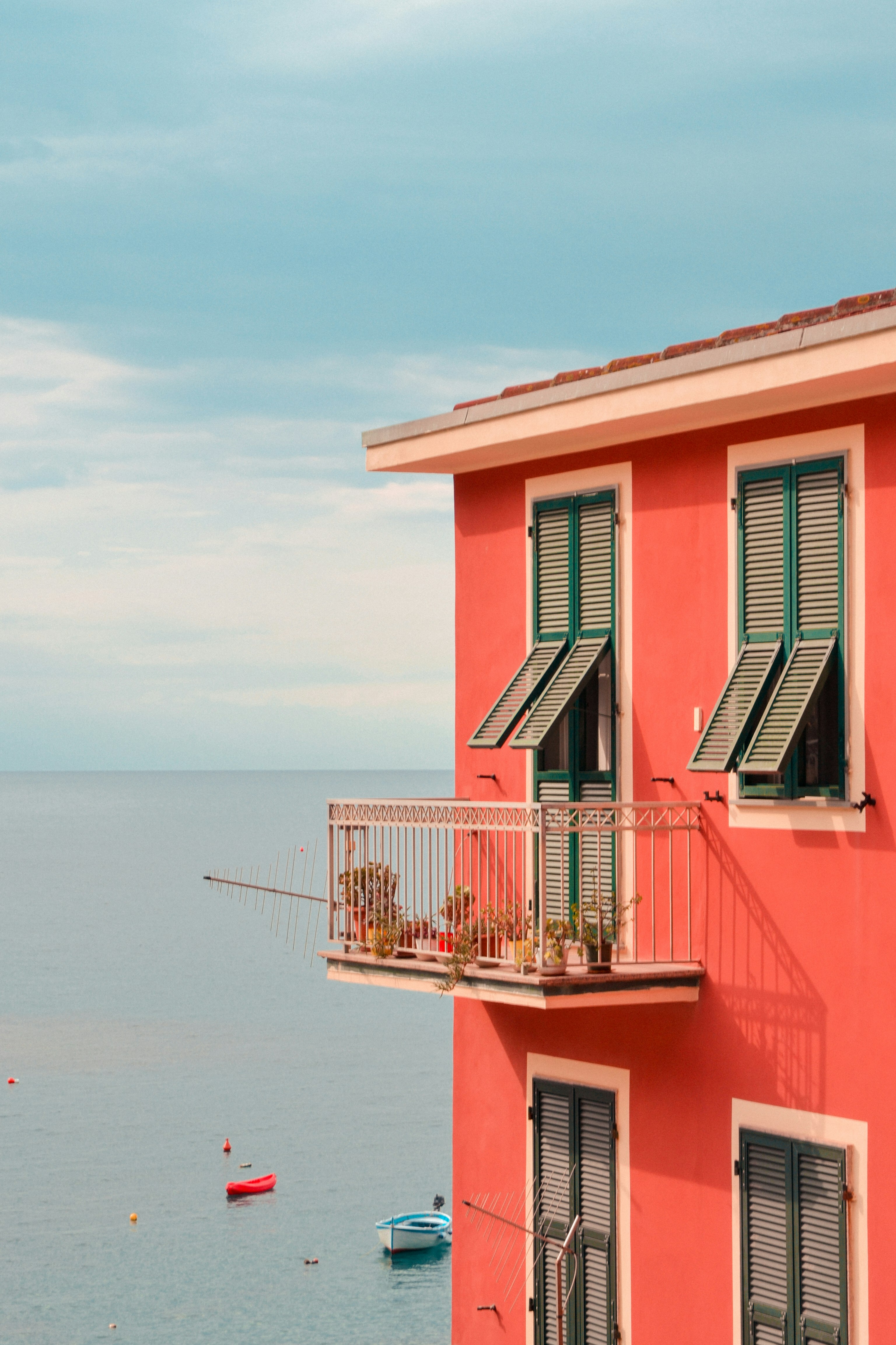 pink and white concrete house near body of water during daytime