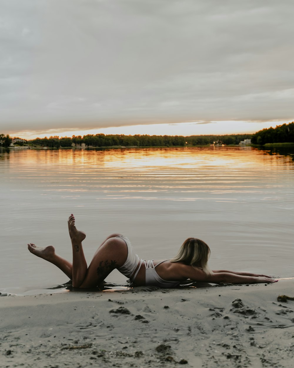 woman in white bikini lying on the beach during daytime