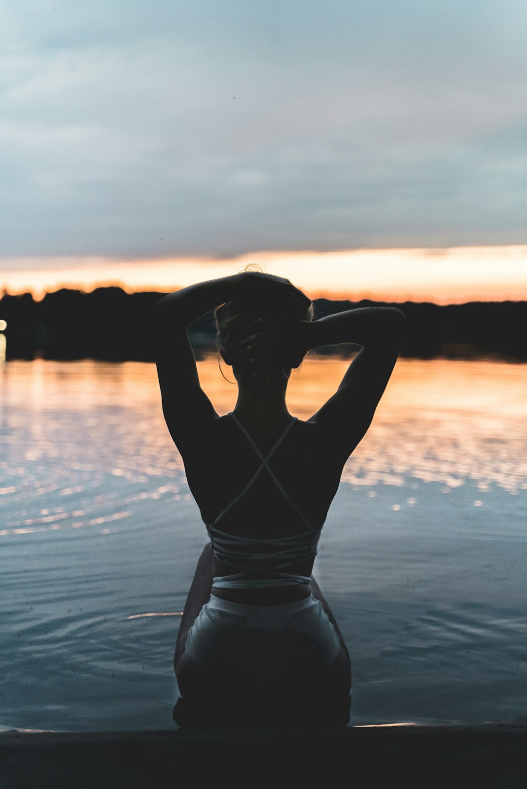 woman in black tank top standing on seashore during sunset