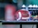 A football is resting on a flat surface, surrounded by various sports bottles and gear. The background is blurred, emphasizing the football and the objects on the table.