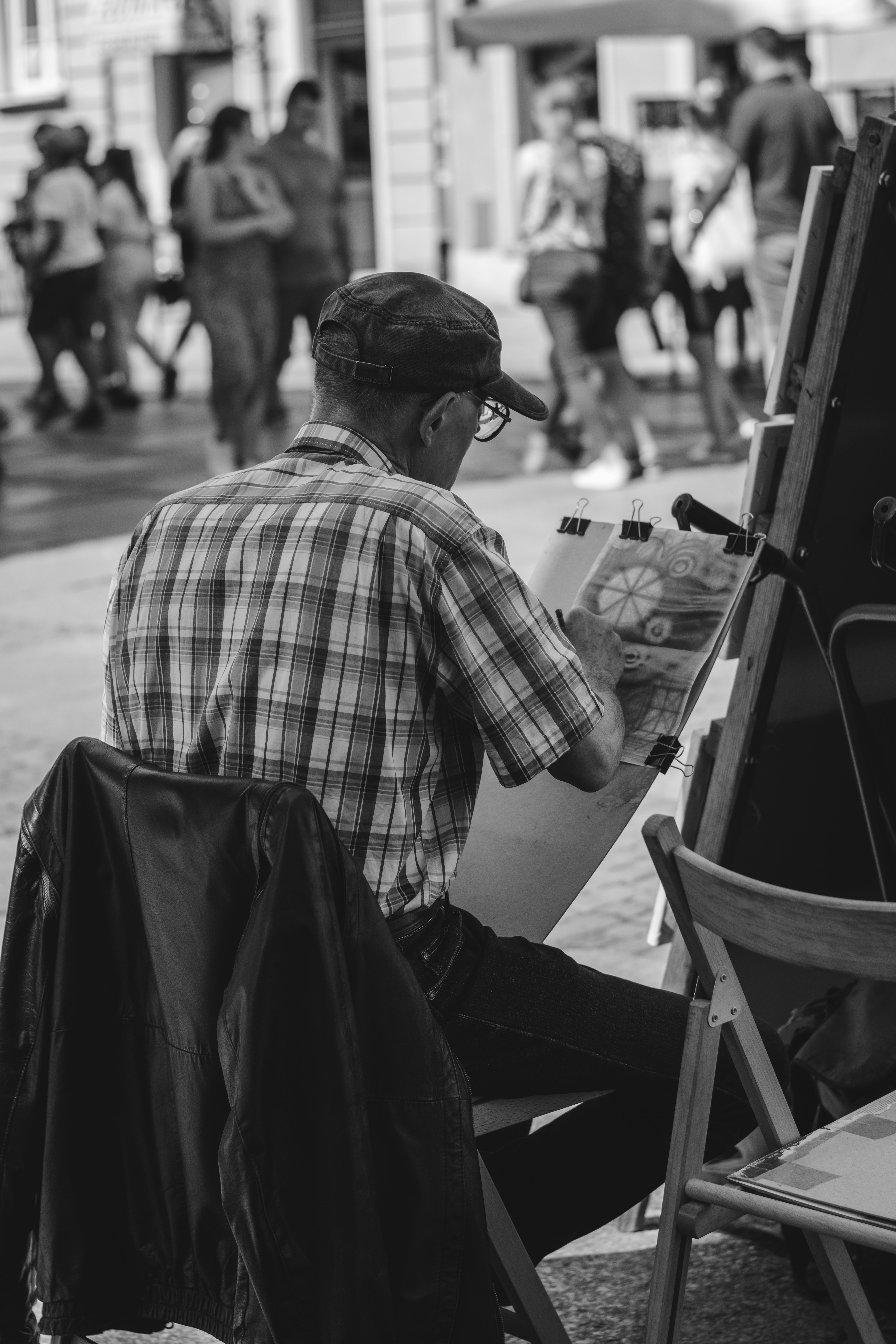 man in white and black plaid dress shirt and black pants sitting on chair