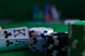 A casino scene featuring two playing cards, the ace and king of clubs, partially concealed by a player's hand. Nearby, there are stacks of multicolored poker chips on a green felt table, with blurred colorful background elements suggesting other chip stacks or cards.