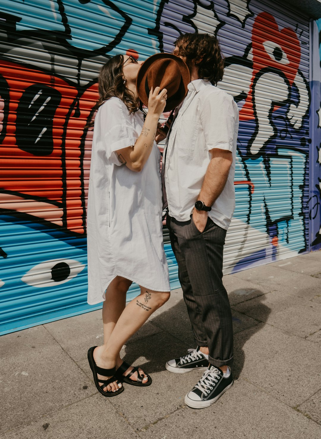 man and woman standing beside each other near red and blue wall during daytime