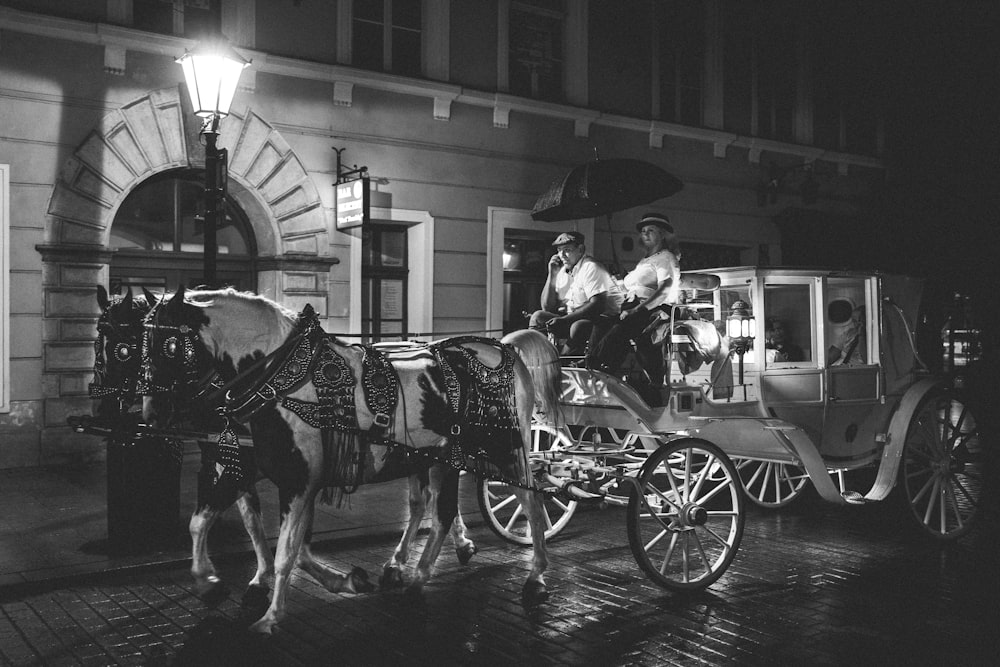 grayscale photo of man riding horse with horse carriage