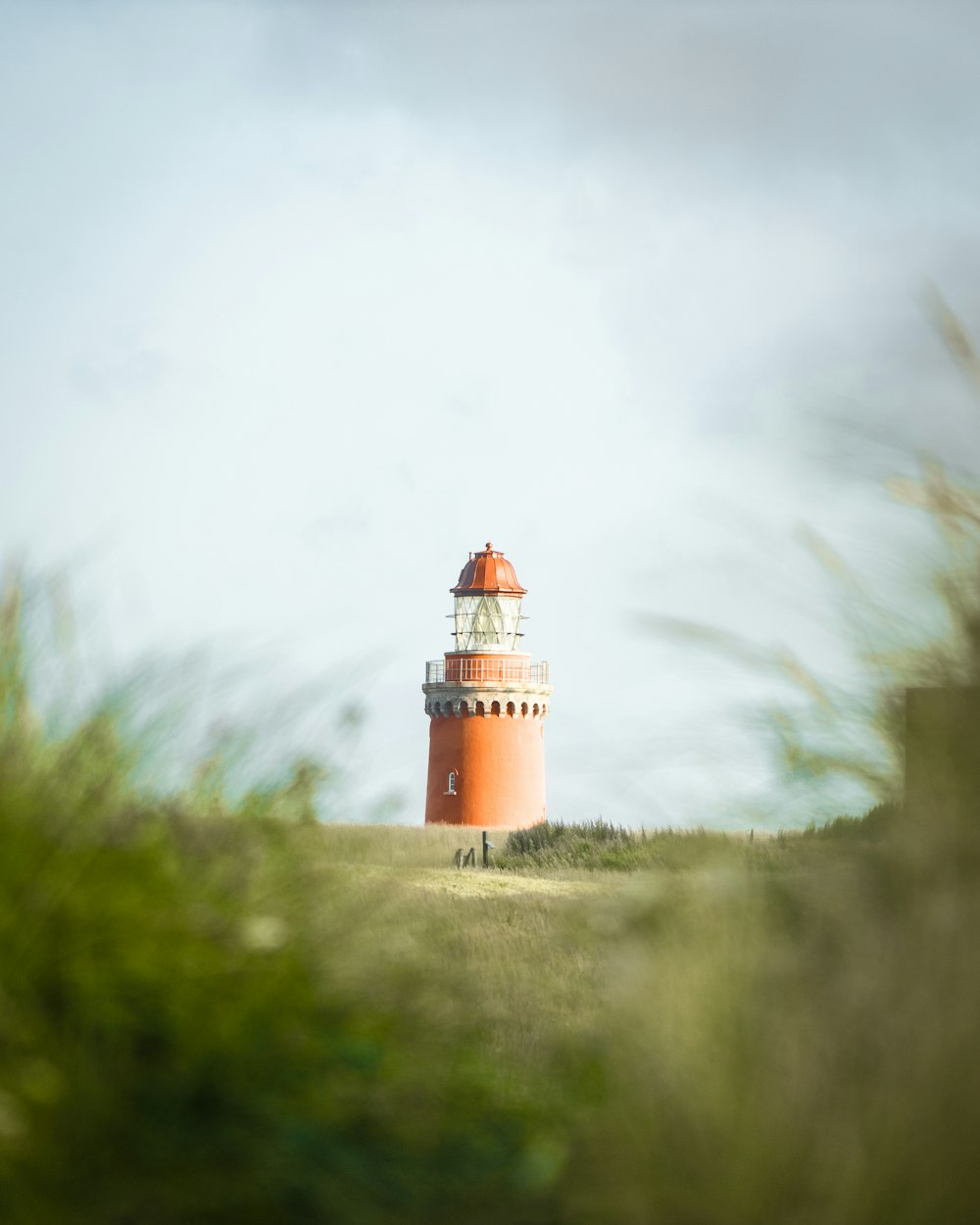 white and red lighthouse on green grass field during daytime