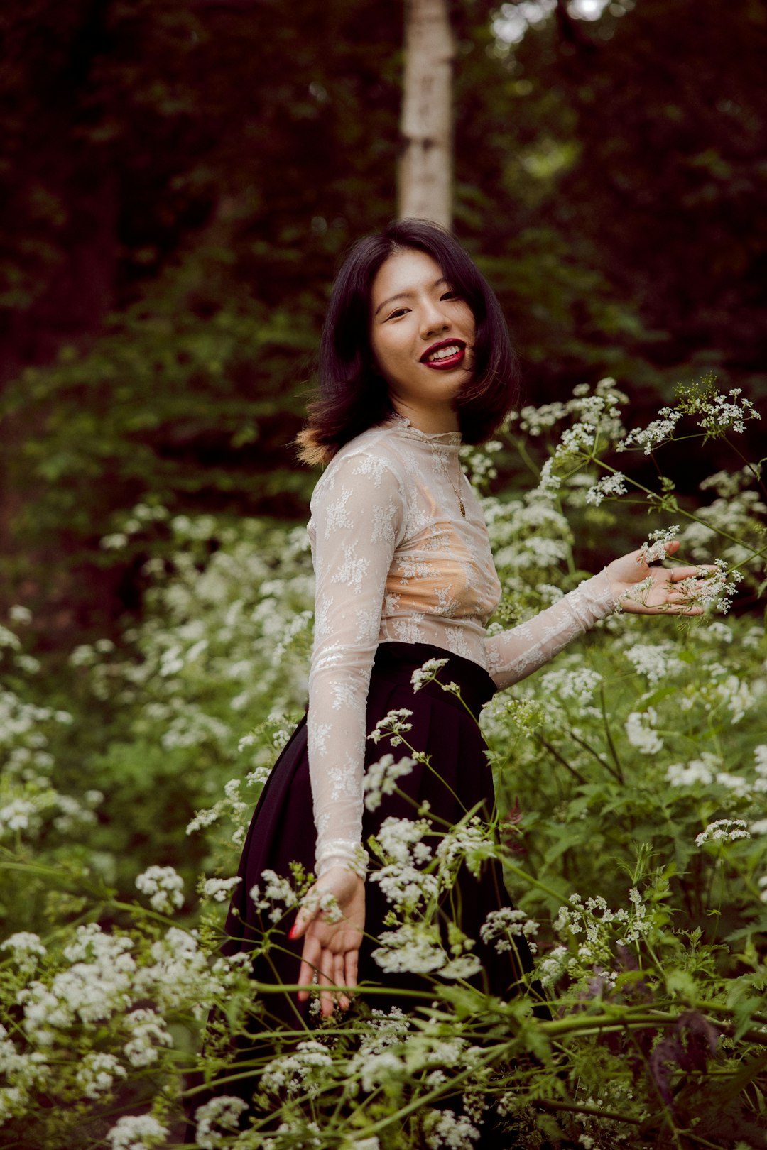 woman in white long sleeve shirt and black skirt standing on green grass field during daytime