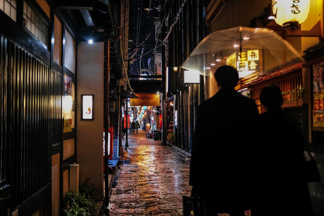 man in black coat walking on street during nighttime