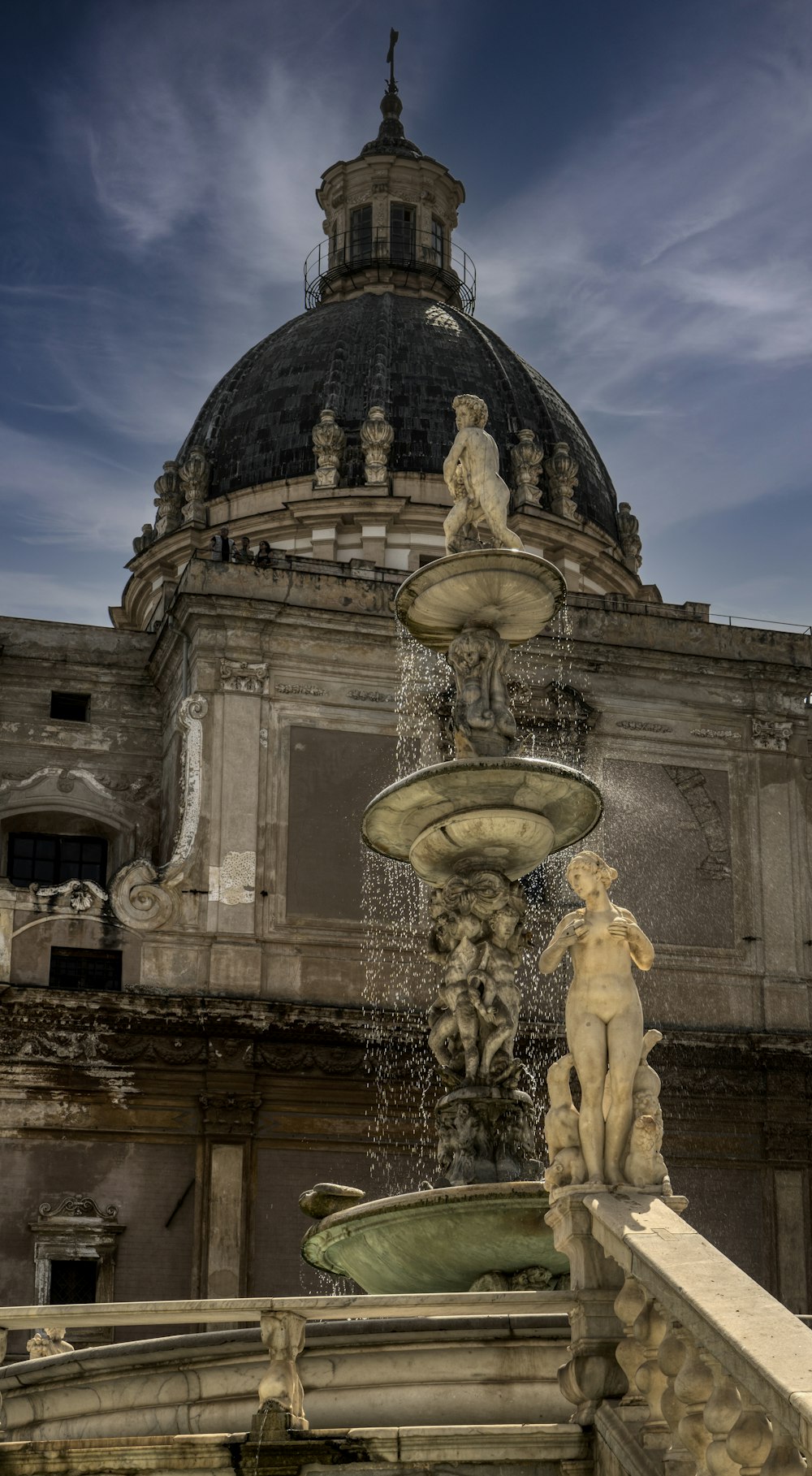 gold statue fountain in front of gray concrete building during night time