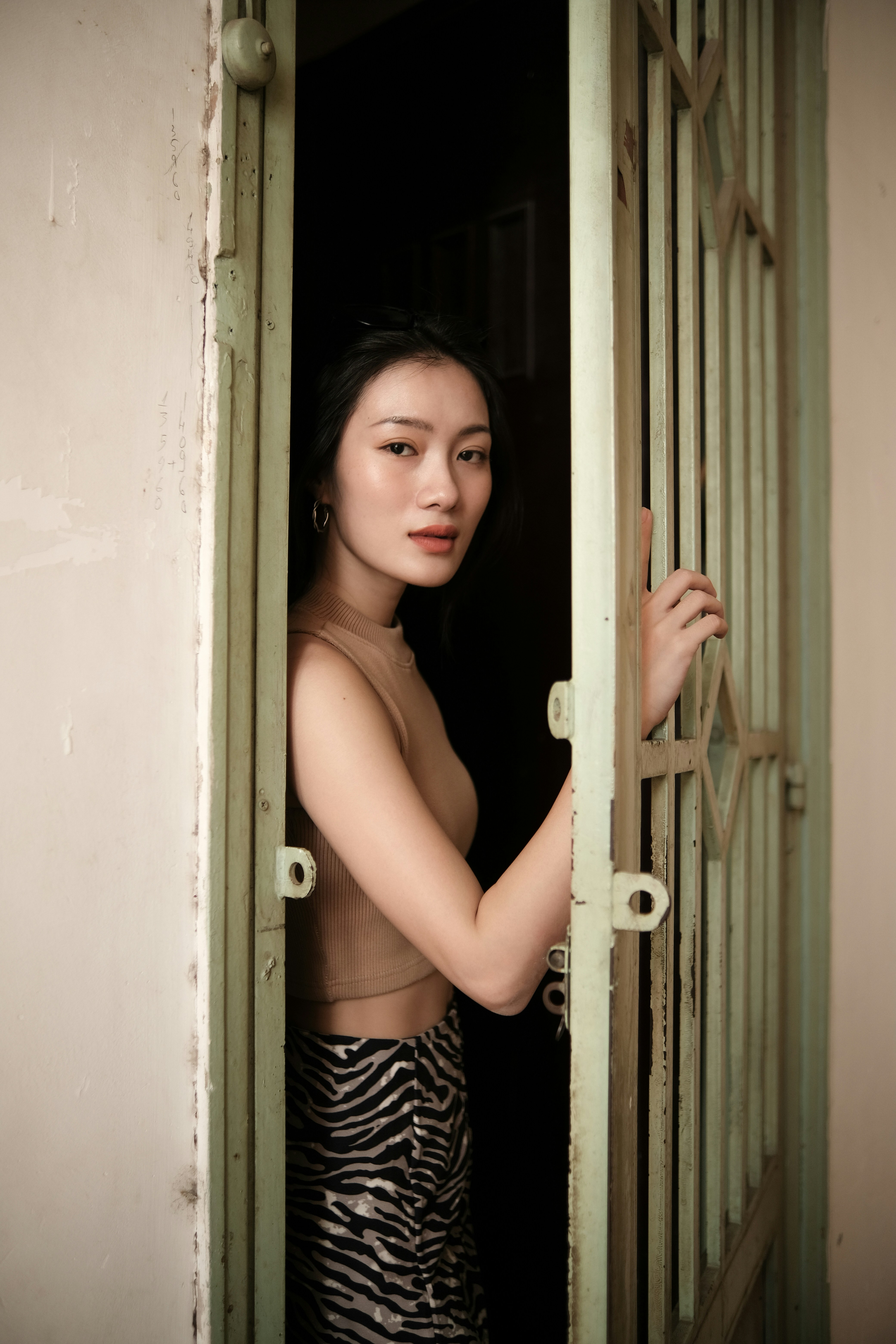girl in black and white stripe tank top standing beside white wooden door