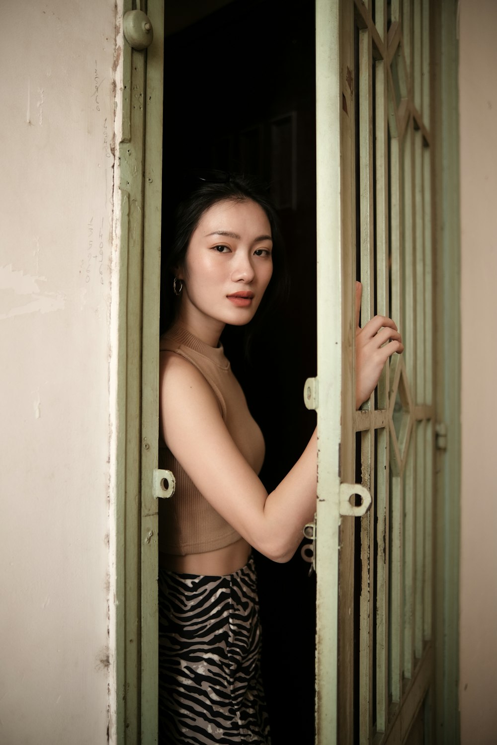 girl in black and white stripe tank top standing beside white wooden door