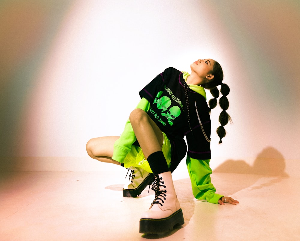 boy in black and green t-shirt and black pants sitting on floor