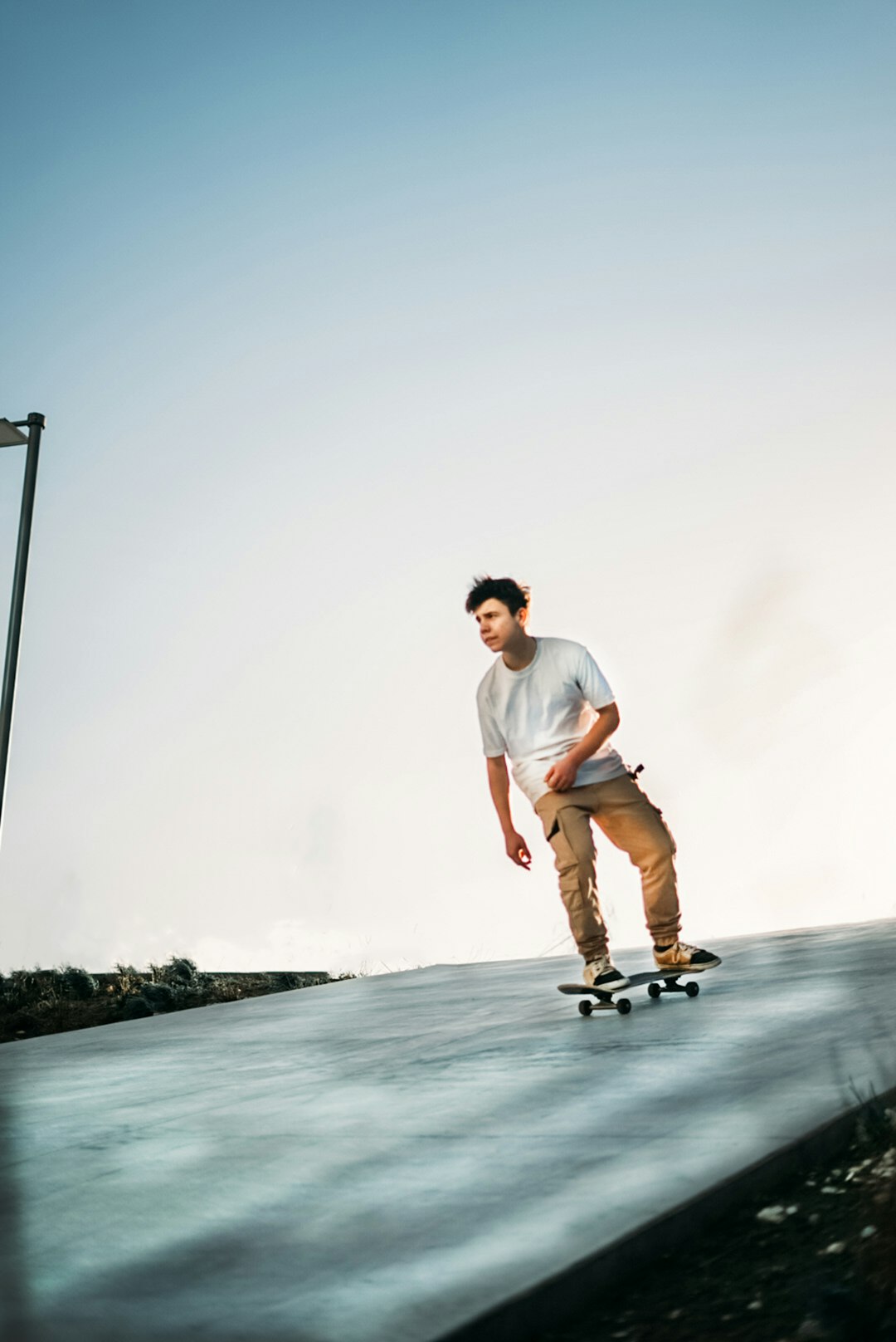 man in white t-shirt and brown shorts standing on skateboard during daytime