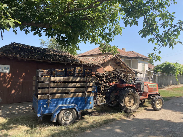 A cheerful customer smiling next to a tractor loaded with boxes of agricultural supplies.