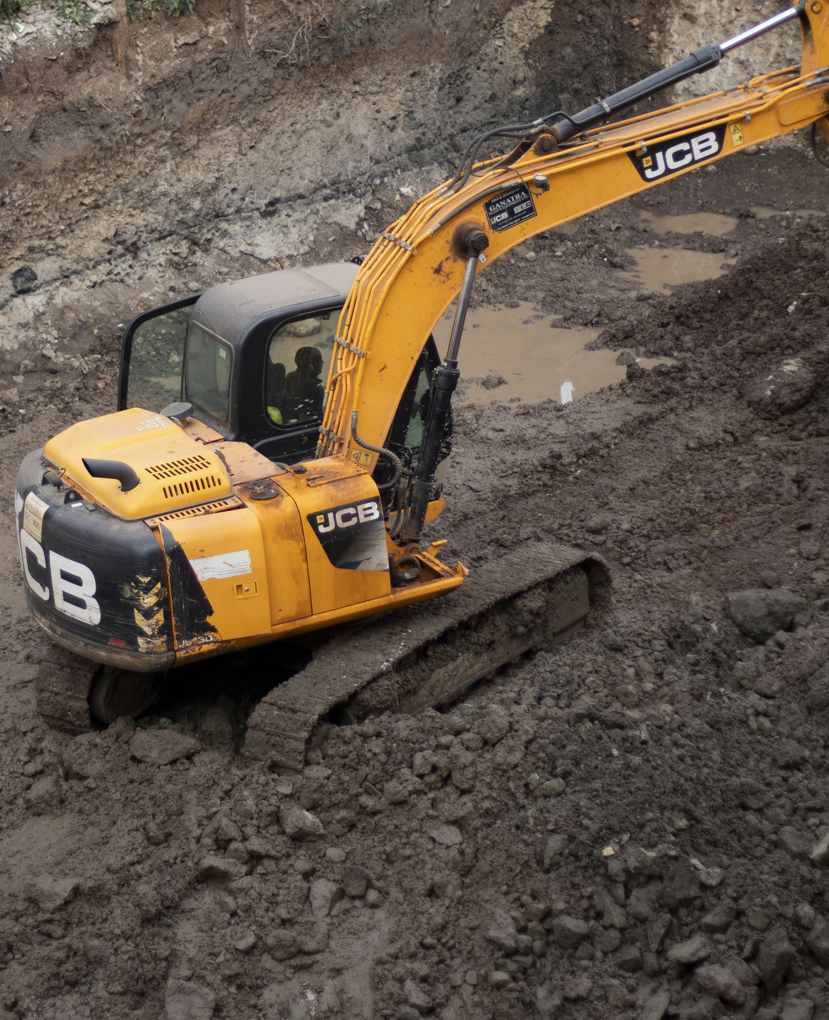 Heavy construction JCB excavator equipment being cleaned with water at a construction site