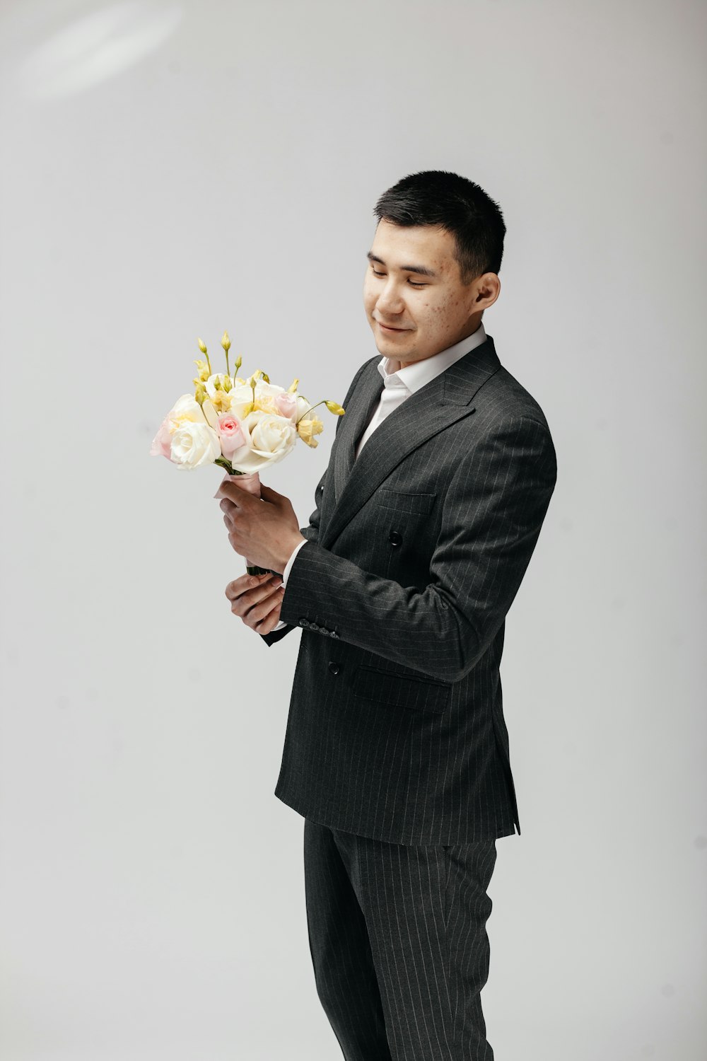 man in black suit holding bouquet of flowers