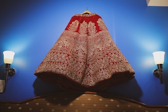 A vibrant traditional dress with colorful embroidery hanging on a wooden hanger.